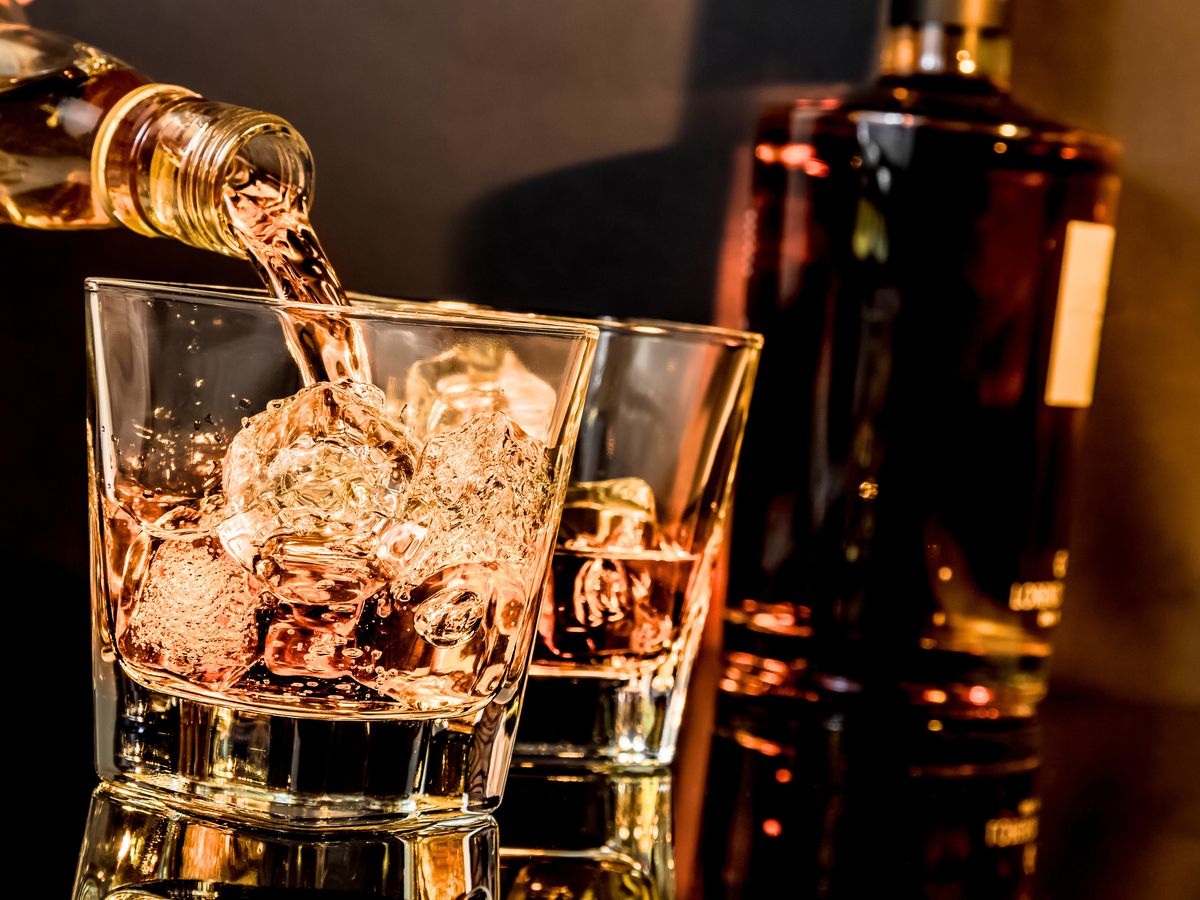 Whisky wird in ein Glas mit Eis gegossen
